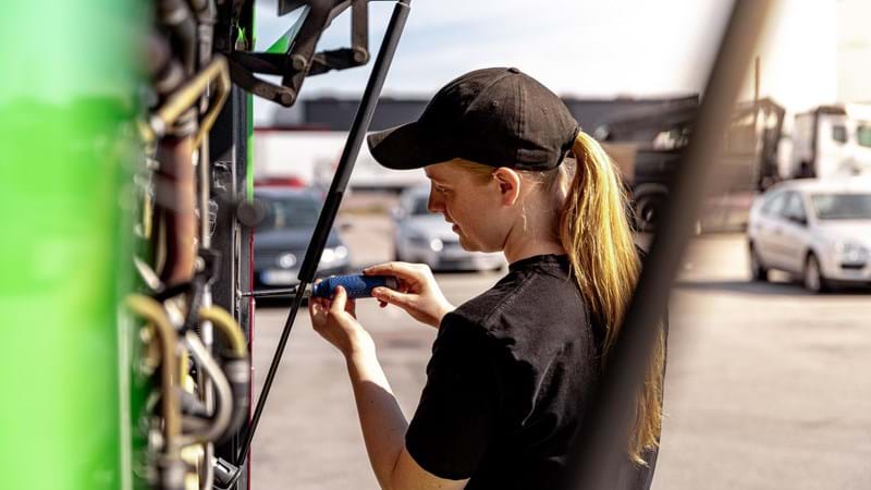 En ung kvinna reparerar en grön buss