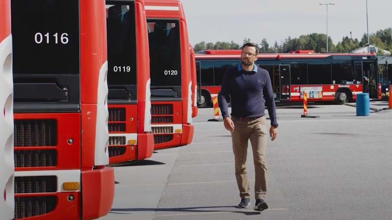 En man går bakom röda bussar